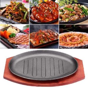 Cast iron hot sizzling plate on wooden tray 